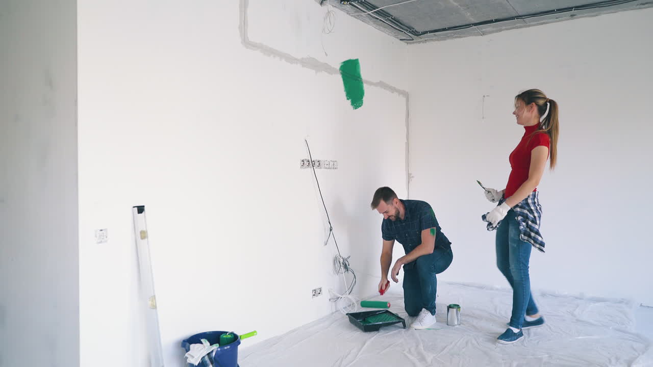 chica y hombre hacen trazos de pintura en los cuerpos del otro en la habitación