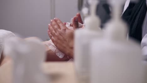 professional cosmetologist holding her hands on woman's face while applying special mask on client's face and neck. camera