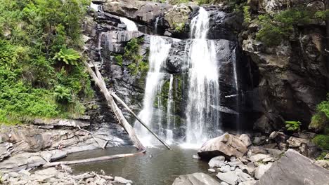 Rotating-drone-shot-of-man-discovering-stunning-hidden-waterfall-in-a-tropical-rainforest