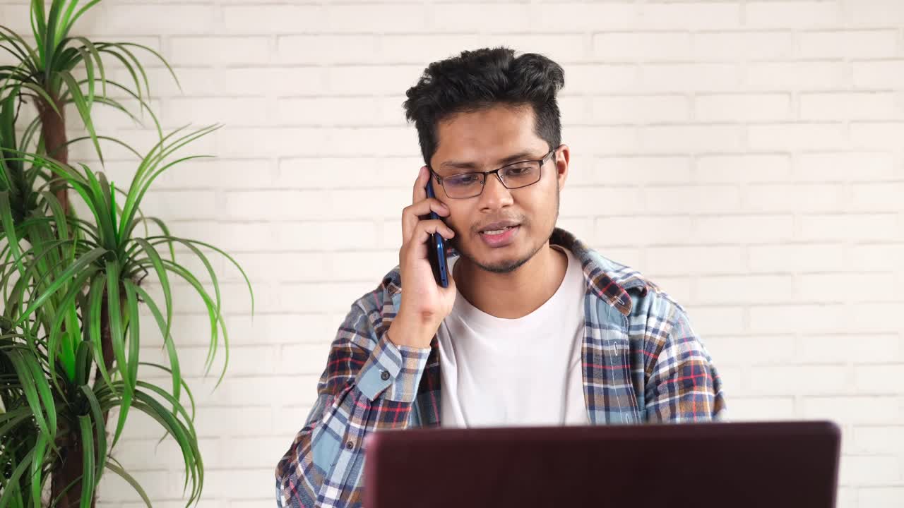 젊은이 가 전화 를 하고 노트북 을 사용 하고 있다