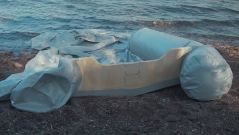 un barco de refugiados desinflado y lúgubre varado en la costa griega