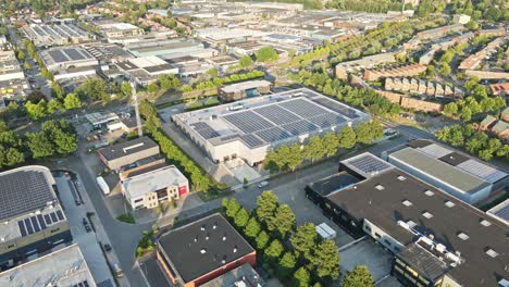 Beautiful-Aerial-of-busy-industrial-terrain-with-solar-panels-on-top-of-large-warehouse