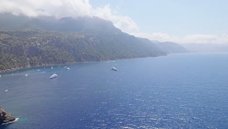 Flying-backward-at-a-mountain-bay-with-cloud´s-in-the-sun-and-many-yacht´s-anchor