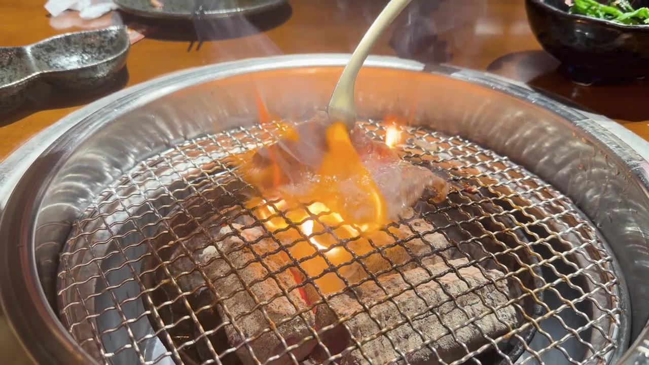 熱い炭火のバーベキューグリルでジュージュー焼ける牛肉をひっくり返す