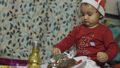 cute-infant-enjoying-Christmas-eve-celebration-at-home-at-night-from-different-angle