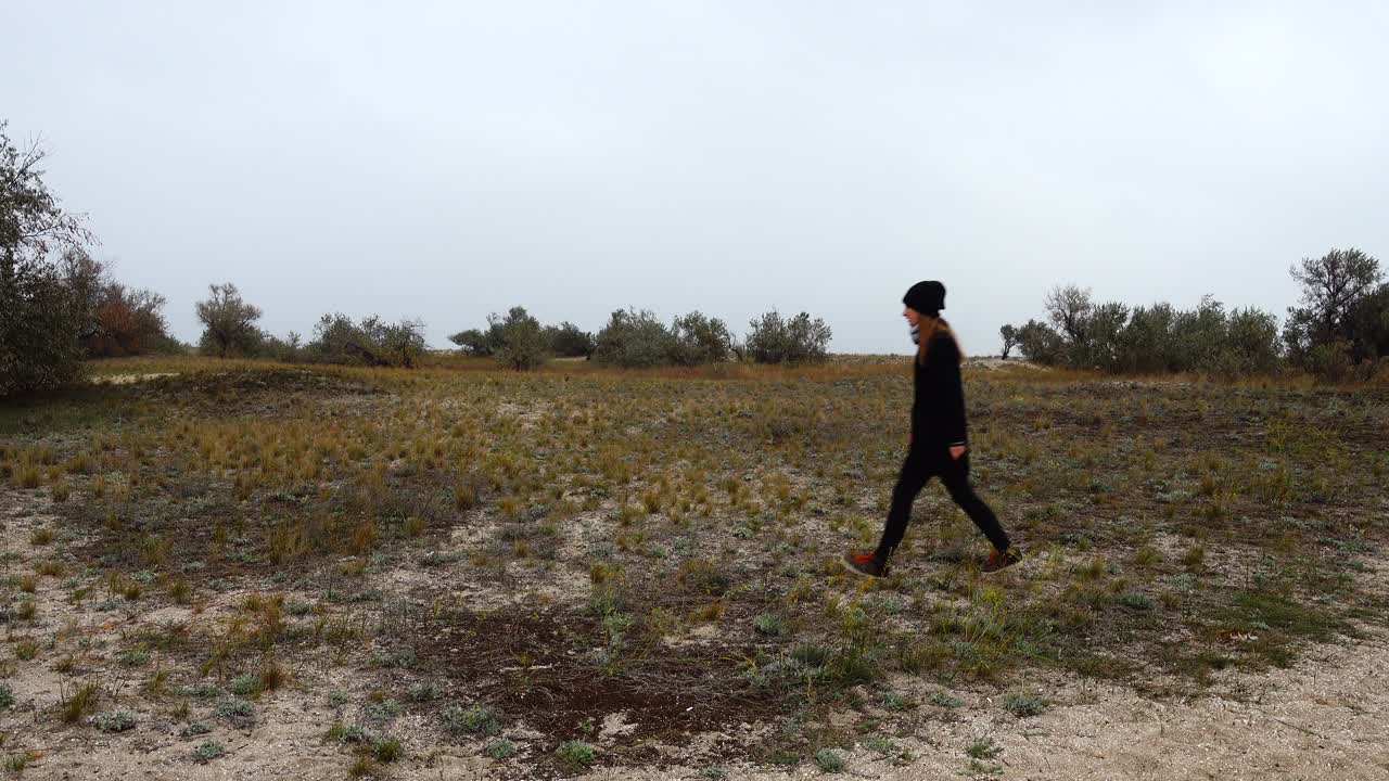 The girl goes on a heathland. Shooting in the fall