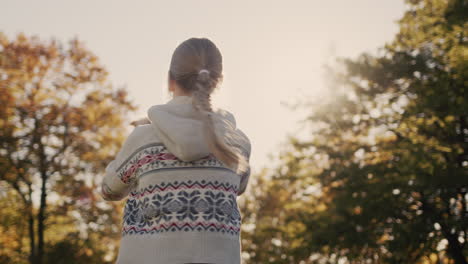 a happy child holds a puppy in his hands and whirls in the rays of the setting sun