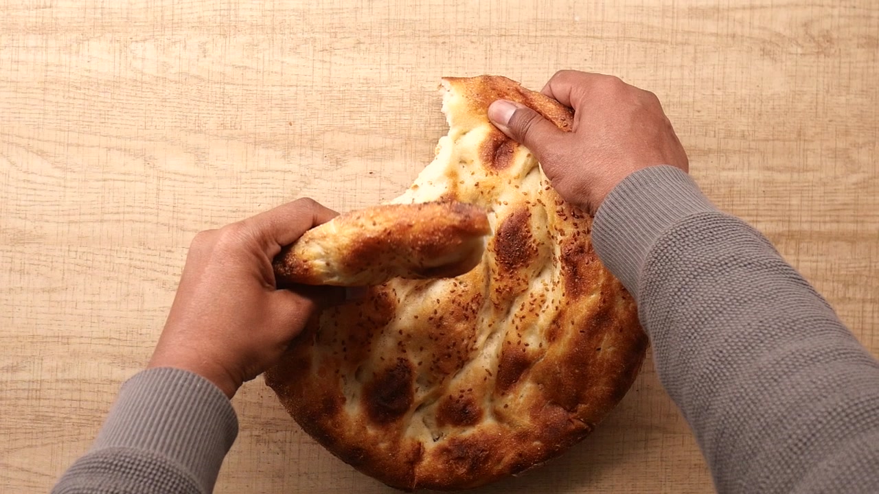 Hands Tearing a Piece of Freshly Baked Turkish Pide Bread
