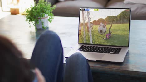 video de una persona sentada en el sofá y viendo un partido de fútbol en una computadora portátil