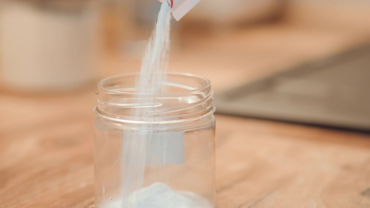 Precise preparation in kitchen. Closeup of powder in glass jar. Calm culinary setting with measured powder container. Detailed view of small powdered amount in glass jar on wooden surface