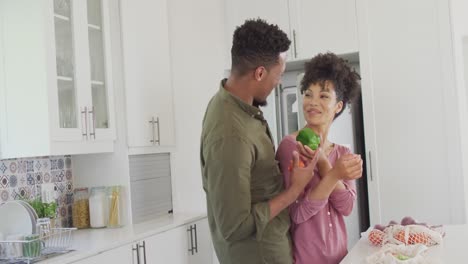 Happy-african-american-couple-with-vegetables-in-kitchen