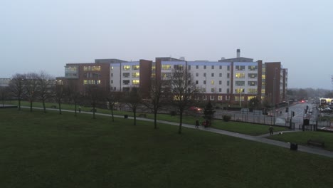 Aerial-view-British-NHS-hospital-on-misty-wet-damp-morning-park-descent