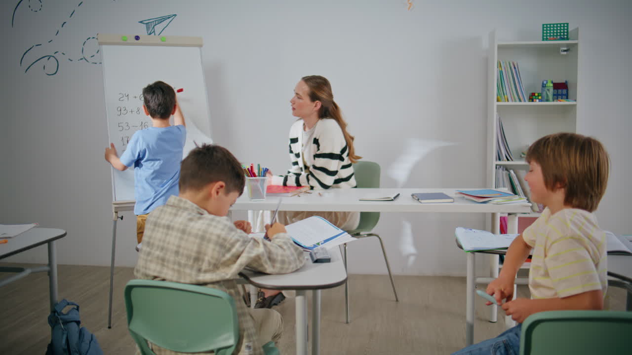 Young schoolteacher asking schoolboy calling to board. Boy writing whiteboard