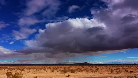 desierto de mojave con nubes tormentosas sobre la cabeza y las montañas distantes en silueta - vista aérea deslizante