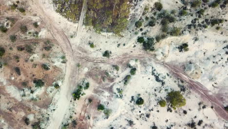 Drone-moving-forward-looking-straight-down-showing-Australian-Outback-with-iconic-red,-orange-and-white-dirt