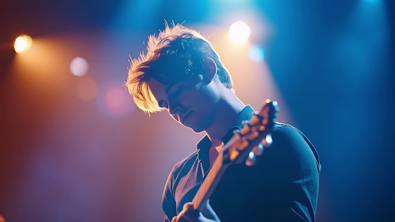 Pria Muda Bermain Gitar Listrik di Atas Panggung dengan Pencahayaan Dramatis
