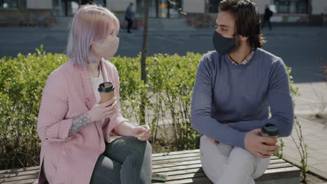 two people talking outdoors, wearing masks