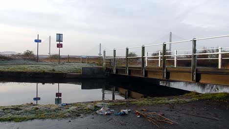 Kanalufergegend,-Das-Sich-Im-Schmalen-Wasserplätscherkanal-Unter-Der-Brückenüberquerung-Widerspiegelt