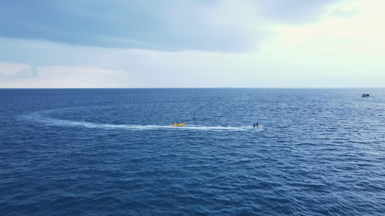 drone dolly torwards pareja montando un barco de tubo de plátano tirado por jet ski