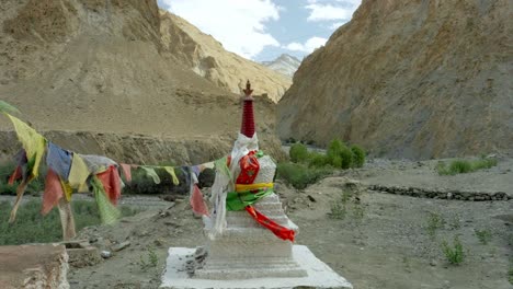 a remote buddhist stupa shrine wrapped in colourful prayer flags in a rugged valley of markah trek in ladakh, india. high altitude worship in scenic panoramic himalayan mountains desert