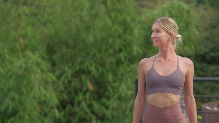 привлекательная блондинка вытягивает руки в позу воина, йога на улице