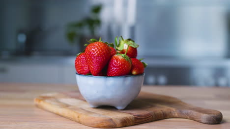 Appetitliche-Erdbeeren-In-Einer-Kleinen-Schüssel-Auf-Einem-Holzbrett