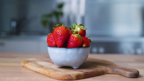 appetizing strawberries in a small bowl on a wooden board
