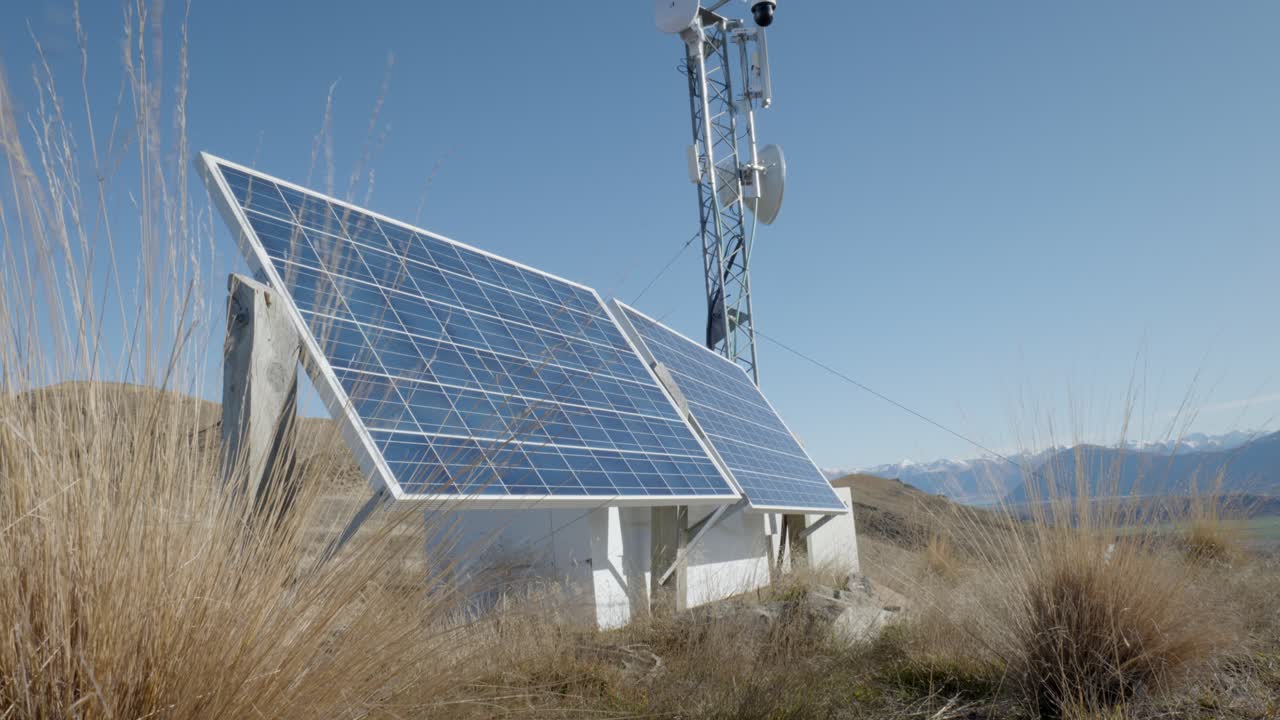 panel solar y torre de transmisión en la montaña nz con hierba seca tussock