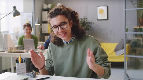 joven trabajador de oficina masculino mirando a la cámara y discutiendo el documento
