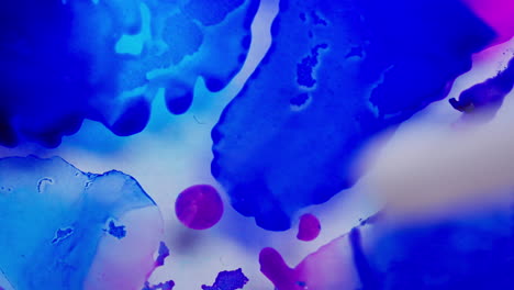 macro view of white ink spreading out forming galaxy with blue ink