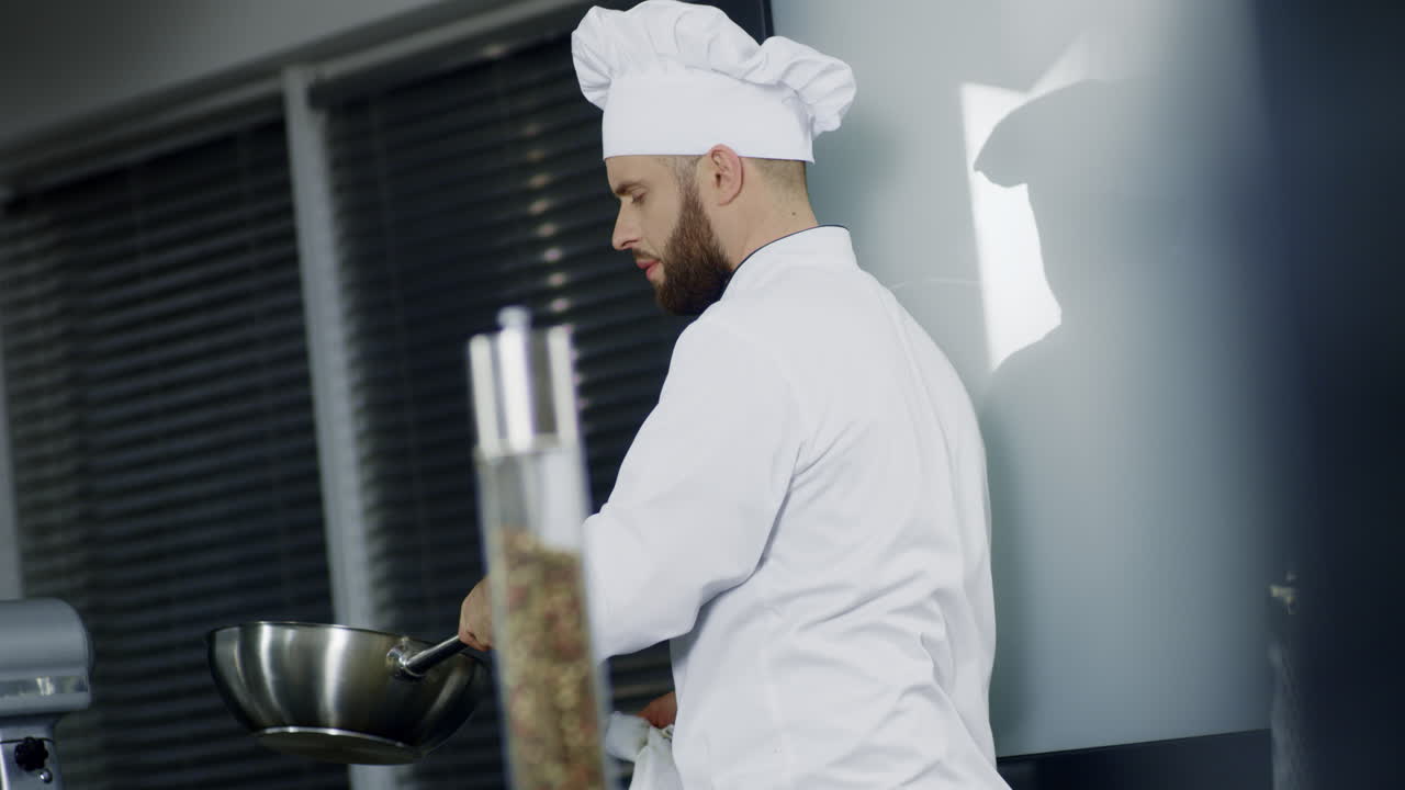 hombre cocinando en wok en la cocina. cocinero enfocado preparando comida asiática