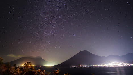 estrellas girando sobre una ciudad brillante, volcanes y lago atitlan en ecuador, lapso de tiempo