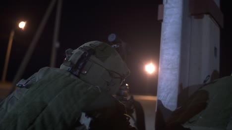 close up of the back of an israeli soldier pointing his rifle covering his friends during combat at night in palestine near gaza