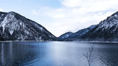 Beautiful-landscape-with-calm-lake-and-snow-covered-mountains-in-winter