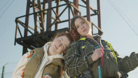 Portrait-Shot-Of-Two-Girls-Looking-At-Camera-While-Backpacking-On-A-Sunny-Day