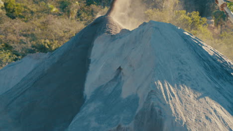 sand falling off conveyor belt, tilt up movement, wide shot, sunny sand quarry