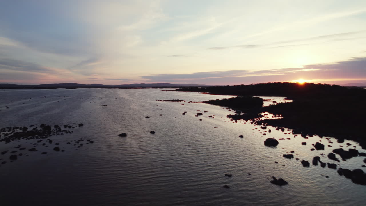 물 속에 작은 섬 실루엣이 있는 거대한 아일랜드 러프 코리브 위로 아름다운 공중 비행