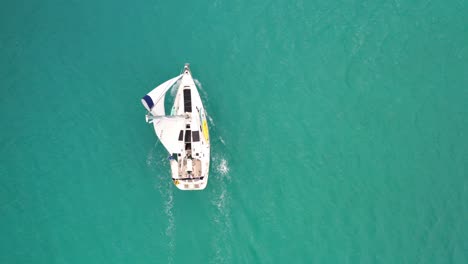 sailboat cruising on turquoise blue sea in summer near the bahamas in caribbean. - aerial