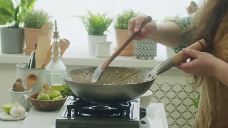 woman stirring ingredients in frying pan