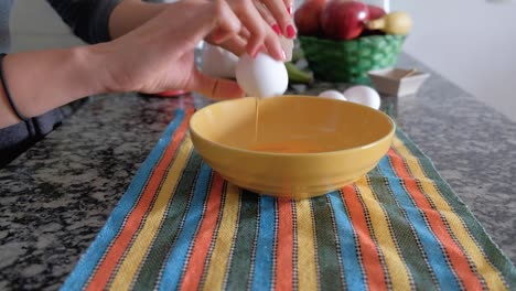 woman hands breaking the shell of an egg and pouring it into a bowl