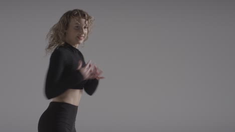 foto de estudio de una joven haciendo práctica de baile contra un fondo gris