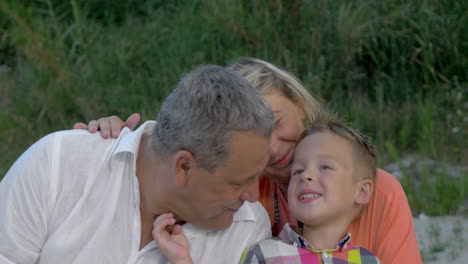 nieto cosquilleando el cuello del abuelo mientras está sentado en la playa