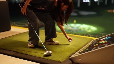 woman playing golf at an indoor driving range at night