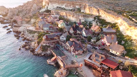 wooden film set village of popeye on malta island coastline, aerial drone view