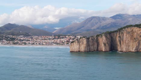 ocean view of seaside gaeta town and montagna spaccata outcropping with mountains in background on sunny day, italy, above aerial approach