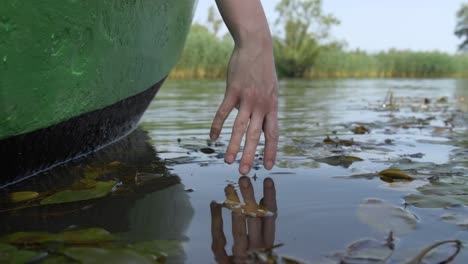 Frau,-Die-Das-Wasser-Mit-Ihrer-Hand-Von-Einem-Boot-Auf-Einem-See-Oder-Fluss-Berührt