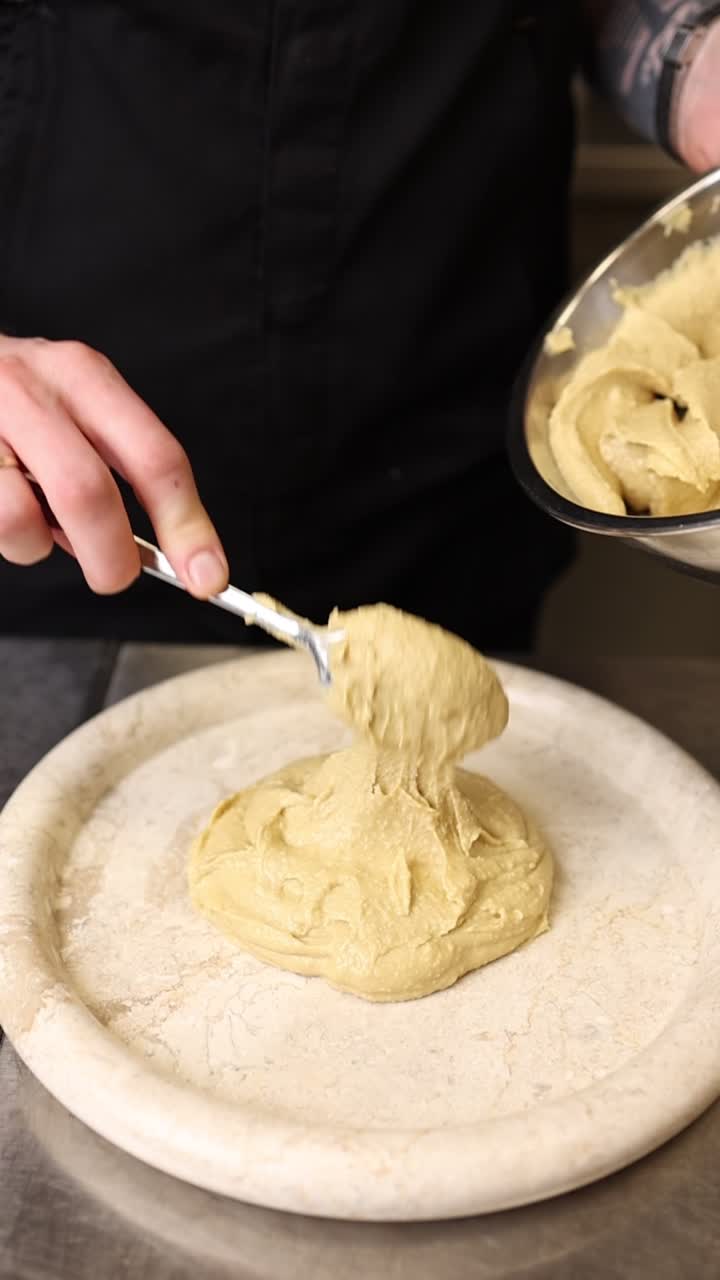Chef Scooping Hummus onto a Serving Plate