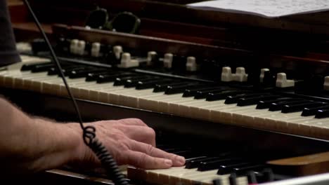 closeup of musician's hands playing organ, fingers over black and white keys.
