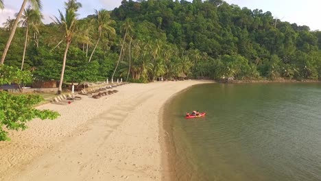 Drohnen-Dolly-Aufnahme-Eines-Kleinen-Tropischen-Strandes-Mit-Kajak-Und-Palmen-Und-Einem-Resort-In-Thailand-Mit-Dschungel
