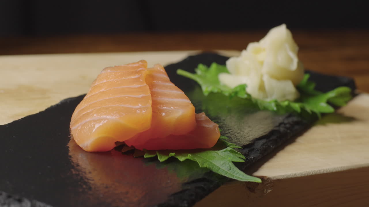 salmón crudo y sashimi de atún colocados en una bandeja de pizarra